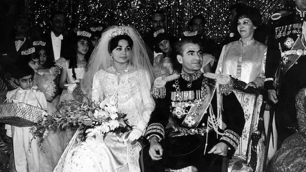 A bride in a white gown and veil sits beside His Majesty in a decorated military uniform — a public domain photograph from The Shah of Iran archive documenting the Pahlavi era.