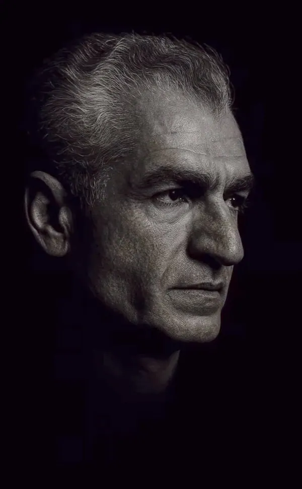 A close-up black and white portrait of an older man with grey hair looking to the side — a public domain photograph from The Shah of Iran archive documenting the Pahlavi era.