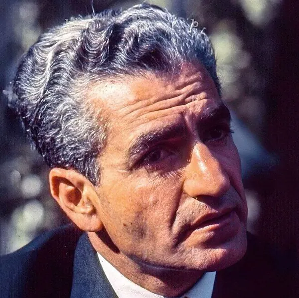A close-up portrait of His Majesty with grey hair wearing a dark suit and white shirt — a public domain photograph from The Shah of Iran archive documenting the Pahlavi era.