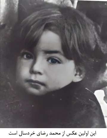 A close-up portrait of a young child with dark hair and eyes looking toward the camera — a public domain photograph from The Shah of Iran archive documenting the Pahlavi era.