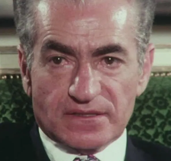 A close-up portrait of an older man wearing a dark suit, white shirt, and patterned tie — a public domain photograph from The Shah of Iran archive documenting the Pahlavi era.