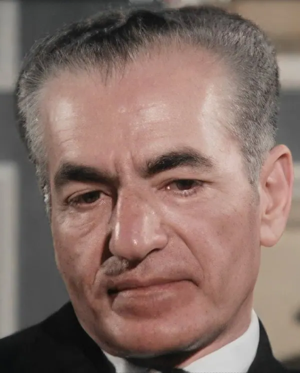 A close-up portrait of an older man with graying hair wearing a dark suit and white collar — a public domain photograph from The Shah of Iran archive documenting the Pahlavi era.