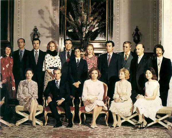 A group of men in suits and women in dresses pose for a formal indoor group portrait — a public domain photograph from The Shah of Iran archive documenting the Pahlavi era.