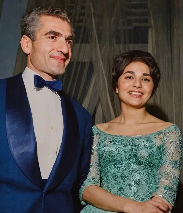 His Majesty, the Shah of Iran in a blue tuxedo and Farah Pahlavi, Empress of Iran, in a green lace dress smile for a portrait — a public domain photograph from The Shah of Iran archive documenting the Pahlavi era.