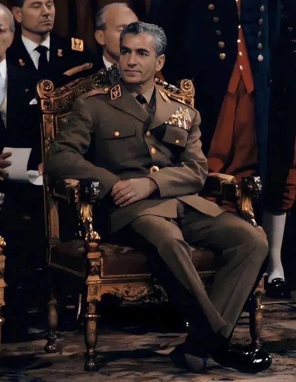 His Majesty, the Shah of Iran in a brown military uniform with medals sits in an ornate gold chair — a public domain photograph from The Shah of Iran archive documenting the Pahlavi era.