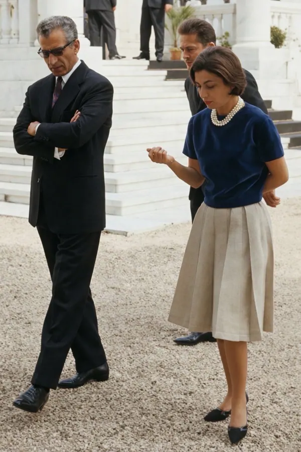 His Majesty, the Shah of Iran in a dark suit and Farah Pahlavi, Empress of Iran, in a blue top and beige skirt walk outdoors — a public domain photograph from The Shah of Iran archive documenting the Pahlavi era.