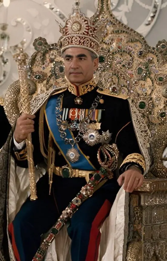His Majesty, the Shah of Iran in a decorated military uniform and ornate crown sits on a jeweled throne holding a scepter — a public domain photograph from The Shah of Iran archive documenting the Pahlavi era.