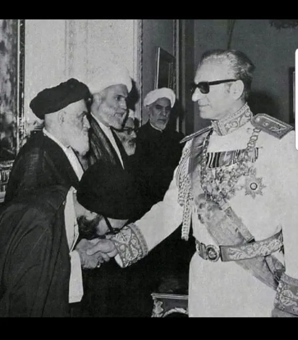 His Majesty, the Shah of Iran in a decorated military uniform shakes hands with His Majesty wearing a dark robe and cap — a public domain photograph from The Shah of Iran archive documenting the Pahlavi era.