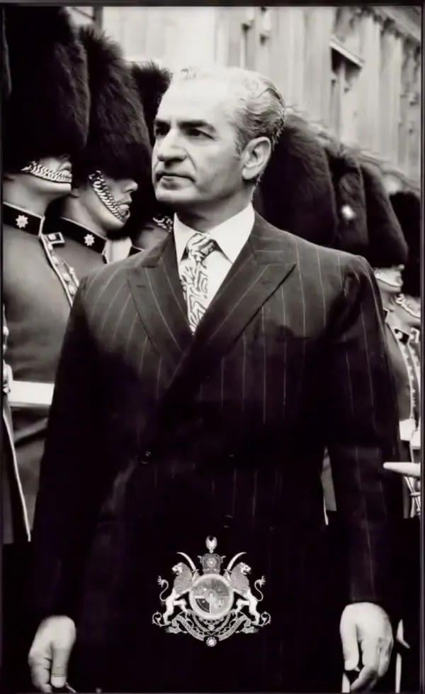 His Majesty, the Shah of Iran in a pinstripe suit stands before a line of guards wearing tall fur hats — a public domain photograph from The Shah of Iran archive documenting the Pahlavi era.