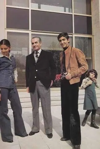 His Majesty, the Shah of Iran in a suit, a young man in a jacket, and two children stand before a building — a public domain photograph from The Shah of Iran archive documenting the Pahlavi era.