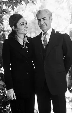 His Majesty, the Shah of Iran in a suit and Farah Pahlavi, Empress of Iran, in a dark jacket stand together outdoors near foliage — a public domain photograph from The Shah of Iran archive documenting the Pahlavi era.