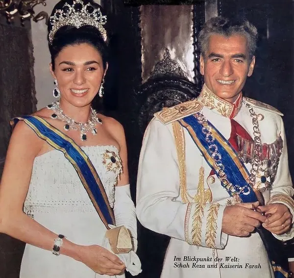 His Majesty, the Shah of Iran in a white military uniform and Farah Pahlavi, Empress of Iran, in a white gown and tiara stand together — a public domain photograph from The Shah of Iran archive documenting the Pahlavi era.