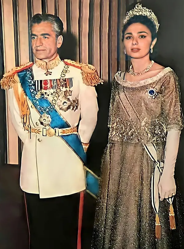 His Majesty, the Shah of Iran in a white military uniform and Farah Pahlavi, Empress of Iran, in a sparkling gown stand side by side — a public domain photograph from The Shah of Iran archive documenting the Pahlavi era.