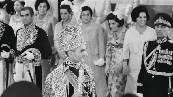 His Majesty, the Shah of Iran in an ornate crown and robe stands before a group of people in formal attire — a public domain photograph from The Shah of Iran archive documenting the Pahlavi era.