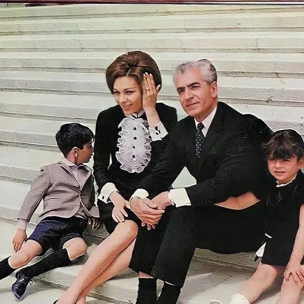 His Majesty, the Shah of Iran, woman, and two children in formal attire sit together on a set of wide white steps — a public domain photograph from The Shah of Iran archive documenting the Pahlavi era.