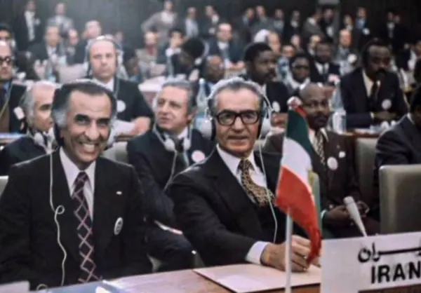 Men in dark suits and headsets sit at a long table in a crowded conference room — a public domain photograph from The Shah of Iran archive documenting the Pahlavi era.