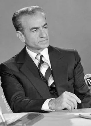 His Majesty, the Shah of Iran in a dark suit and striped tie sits at a table looking to the side — a public domain photograph from The Shah of Iran archive documenting the Pahlavi era.