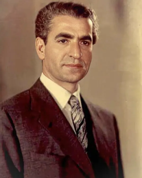 His Majesty, the Shah of Iran in a dark suit, white shirt, and patterned tie poses for a studio portrait — a public domain photograph from The Shah of Iran archive documenting the Pahlavi era.