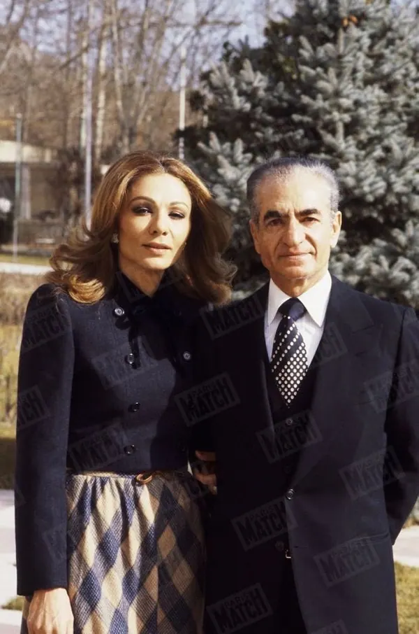 His Majesty, the Shah of Iran in a dark suit and Farah Pahlavi, Empress of Iran, in a dark jacket and patterned skirt stand together — a public domain photograph from The Shah of Iran archive documenting the Pahlavi era.
