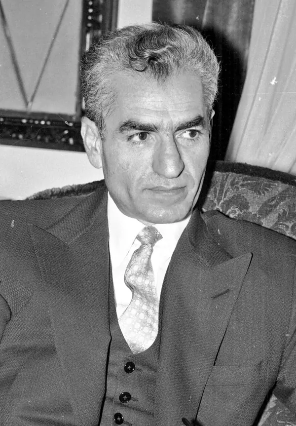 His Majesty, the Shah of Iran in a suit, vest, and tie looks slightly to the side in a portrait — a public domain photograph from The Shah of Iran archive documenting the Pahlavi era.