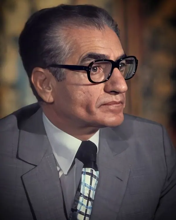 His Majesty, the Shah of Iran wearing black glasses, a grey suit, and a patterned tie looks toward the side — a public domain photograph from The Shah of Iran archive documenting the Pahlavi era.