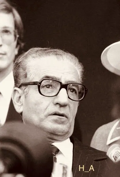 His Majesty, the Shah of Iran with glasses and a suit looks forward in a close-up shot — a public domain photograph from The Shah of Iran archive documenting the Pahlavi era.