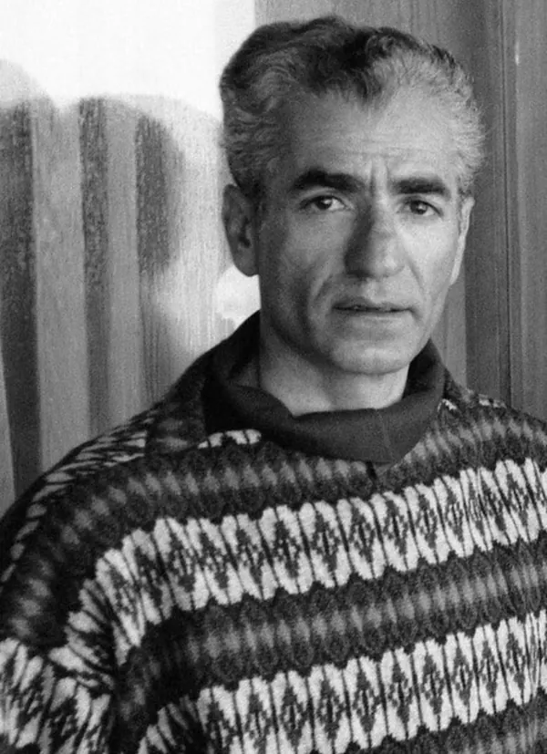 His Majesty, the Shah of Iran with graying hair wears a patterned sweater and looks directly at the camera — a public domain photograph from The Shah of Iran archive documenting the Pahlavi era.