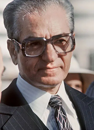 His Majesty, the Shah of Iran with grey hair and glasses wears a pinstripe suit and patterned tie — a public domain photograph from The Shah of Iran archive documenting the Pahlavi era.