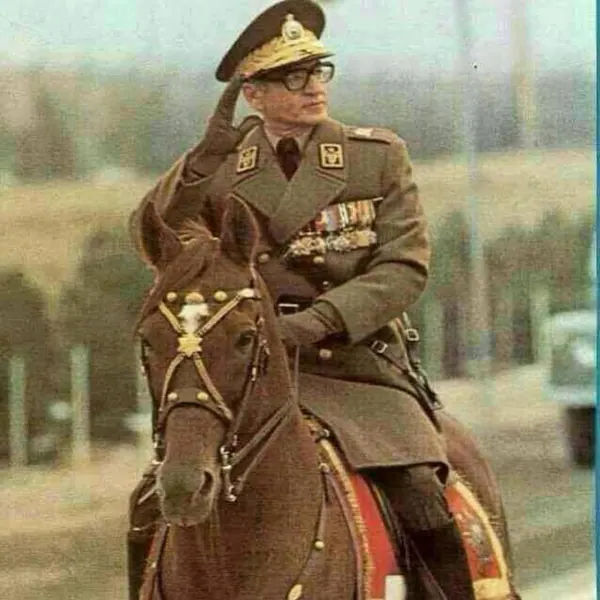 An older man in a military uniform and cap salutes while sitting atop a brown horse — a public domain photograph from The Shah of Iran archive documenting the Pahlavi era.