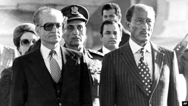 Several men in suits and one man in a military uniform stand together outdoors in a group — a public domain photograph from The Shah of Iran archive documenting the Pahlavi era.
