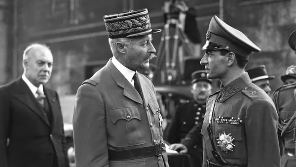 His Majesty, the Shah of Iran, and others in military uniforms face each other while His Majesty in a suit looks on from the side — a public domain photograph from The Shah of Iran archive documenting the Pahlavi era.