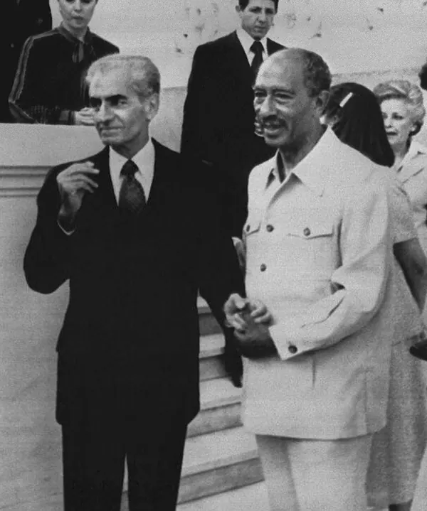 His Majesty, the Shah of Iran, and others in suits stand outdoors near stairs, with other people visible in the background — a public domain photograph from The Shah of Iran archive documenting the Pahlavi era.