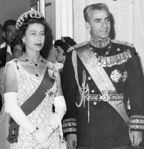 Farah Pahlavi, Empress of Iran, in a jeweled gown and tiara stands beside His Majesty in a decorated military uniform — a public domain photograph from The Shah of Iran archive documenting the Pahlavi era.