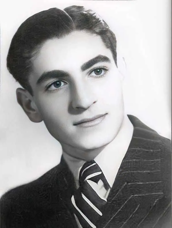 A young man in a pinstripe suit and striped tie looks slightly upward in a studio portrait — a public domain photograph from The Shah of Iran archive documenting the Pahlavi era.