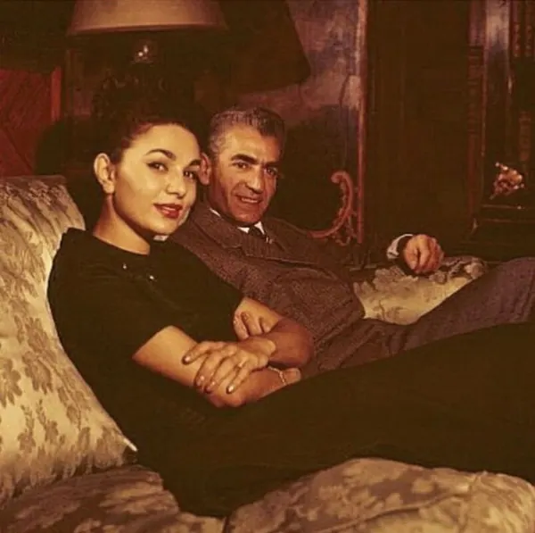 Farah Pahlavi, Empress of Iran, in a black dress and His Majesty in a suit lounge on a sofa — a public domain photograph from The Shah of Iran archive documenting the Pahlavi era.